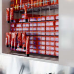 Shelves stocked with rows of Aveda hair color tubes and containers, with hair dye brushes and bowls on a counter below.
