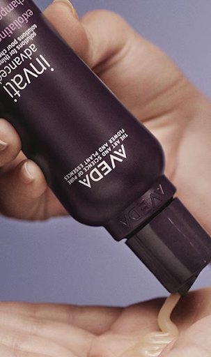 A person dispenses Aveda Invati Advanced hair product from a tube onto their palm.