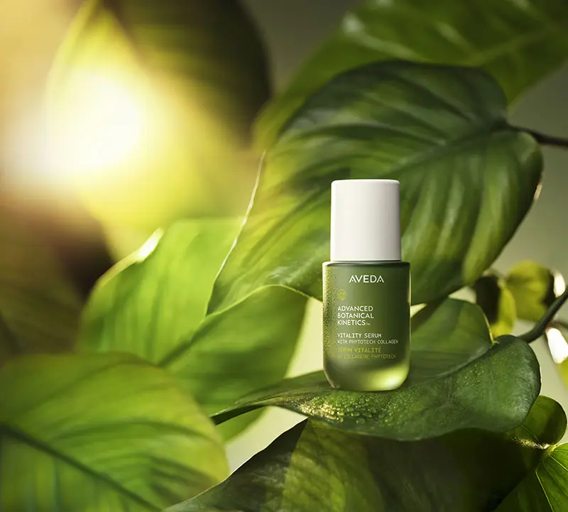 - Spa Bleü in West Dundee, St. Charles and South Barrington, IL A green bottle of Aveda Advanced Botanical Kinetics Vitality Serum rests on large green leaves with sunlight in the background. - Spa Bleü in West Dundee, St. Charles and South Barrington, IL